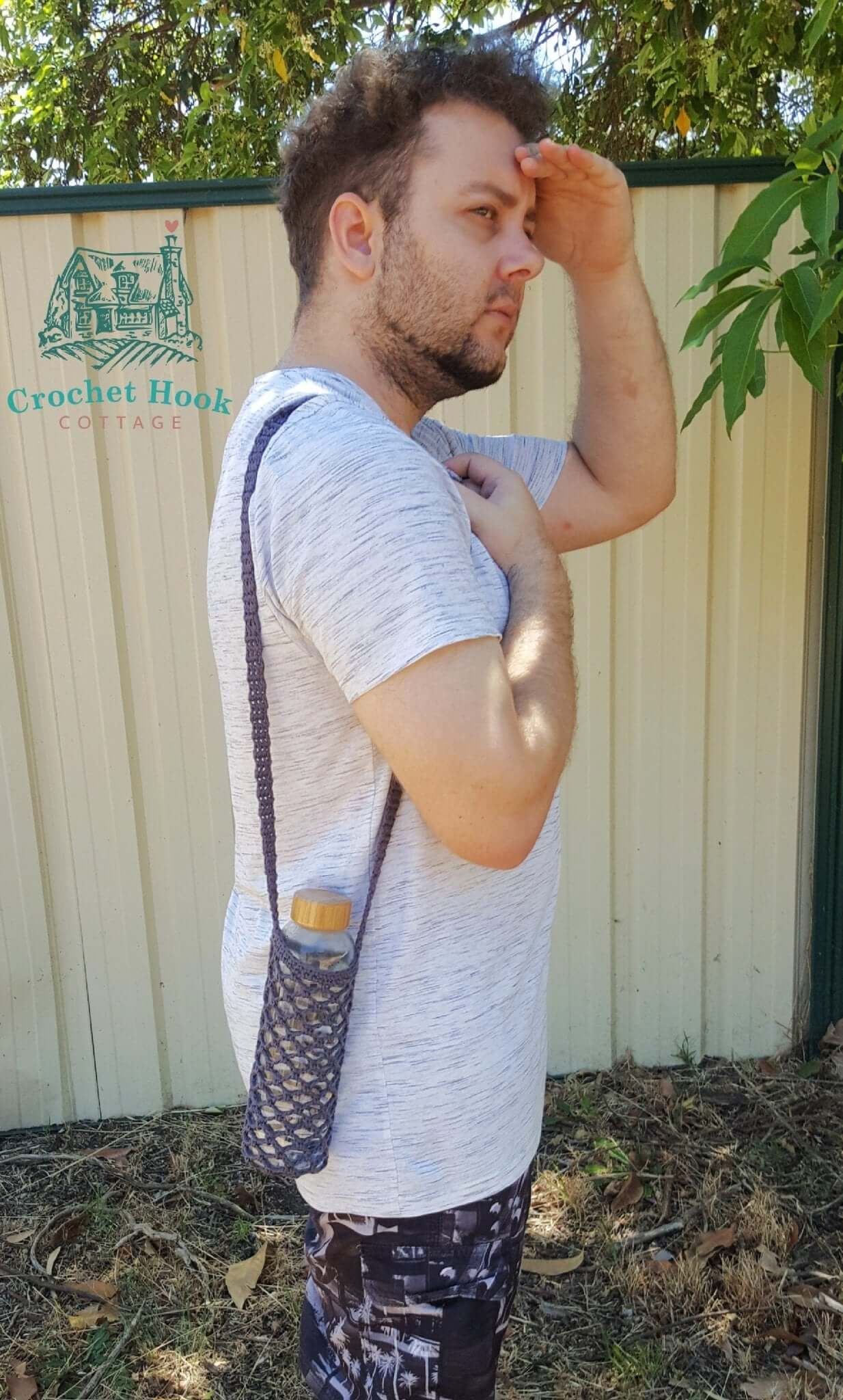 Person using a Bottle Holder, hands free drink bottle bag with shoulder strap, crocheted in 100% cotton yarn, mesh net design with shoulder strap